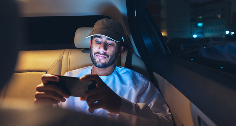 Close up of smiling young urban asian man watching tablet device at home in kitchen at night. Dramatic
